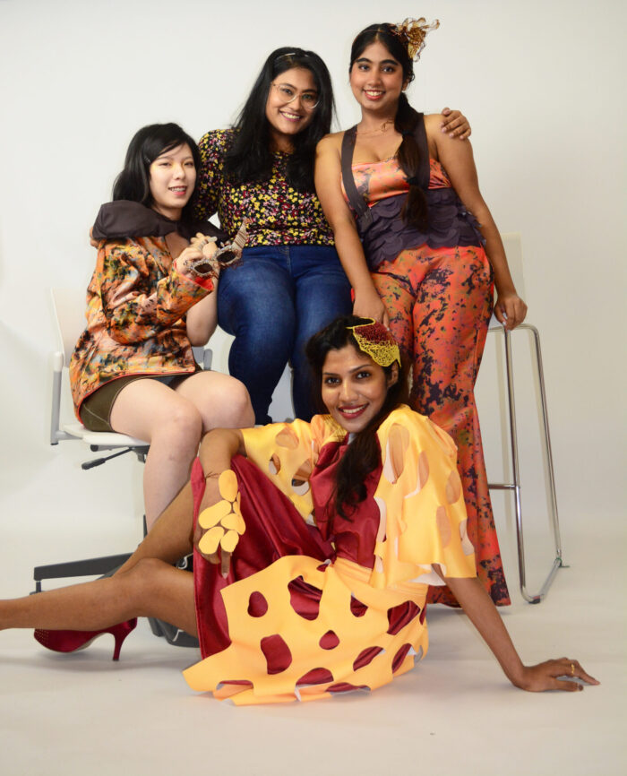 models wear garments created by Sujata Nandi and pose behind her